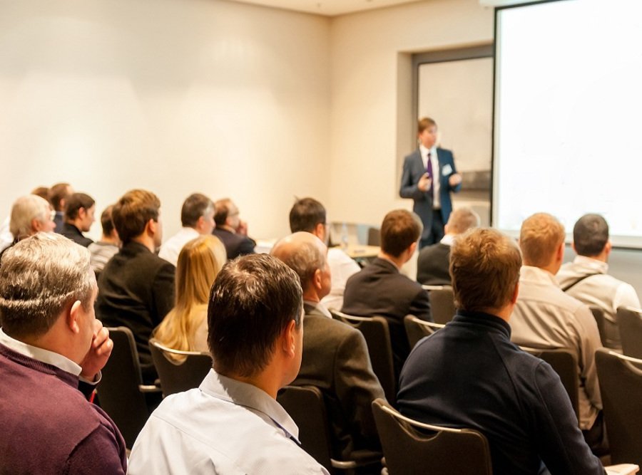People Sitting At The Business Conference And Speaker At The Scr